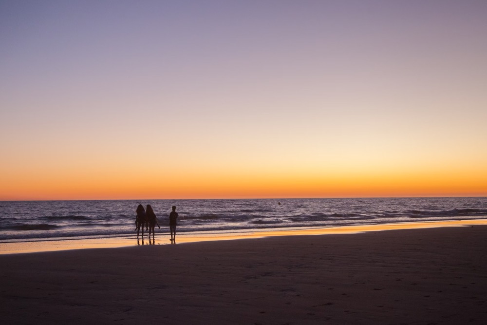 Solo traveler embracing JOMO travel Australia on a quiet beach at sunrise