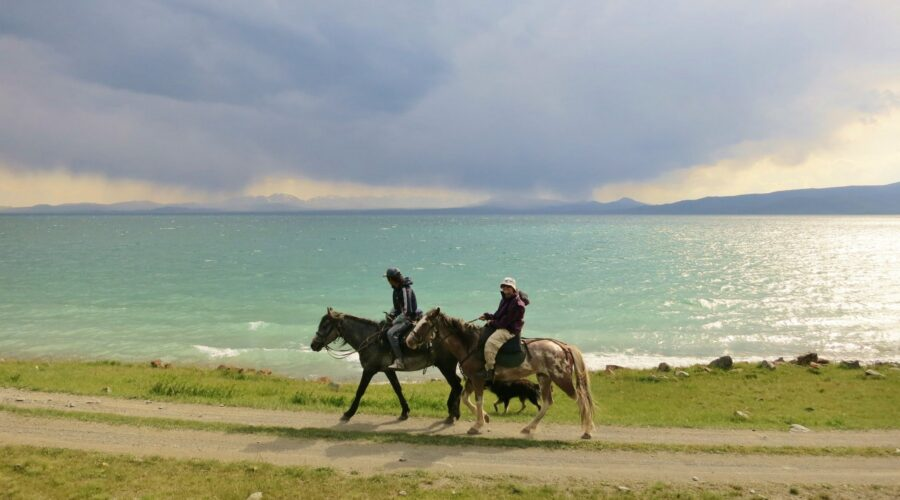 Horseback riders crossing Song Kol Lake β Ultimate independent travel guide to Kyrgyzstan