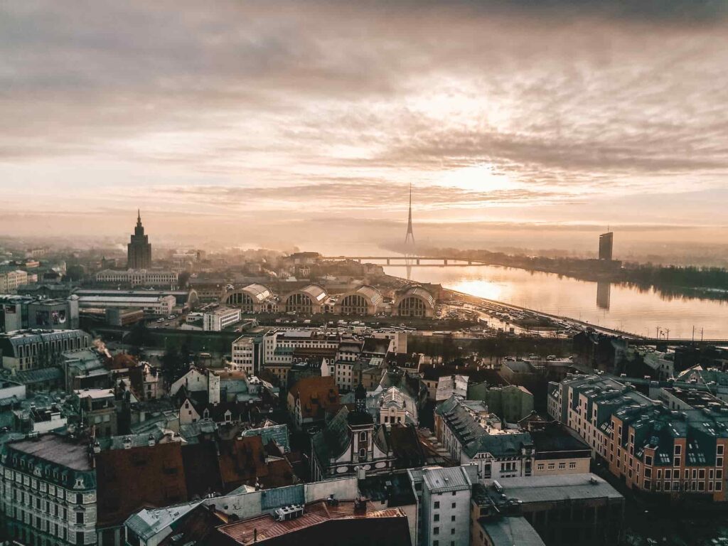 Riga Latvia travel guide – sunrise over cobblestone streets and spires of Old Town with cyclists and cafés