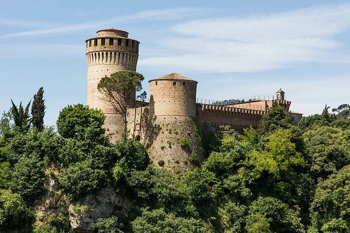 Panoramic view of Brisighella village under a blue sky, showcasing medieval towers and rolling hills – Brisighella Italy travel guide