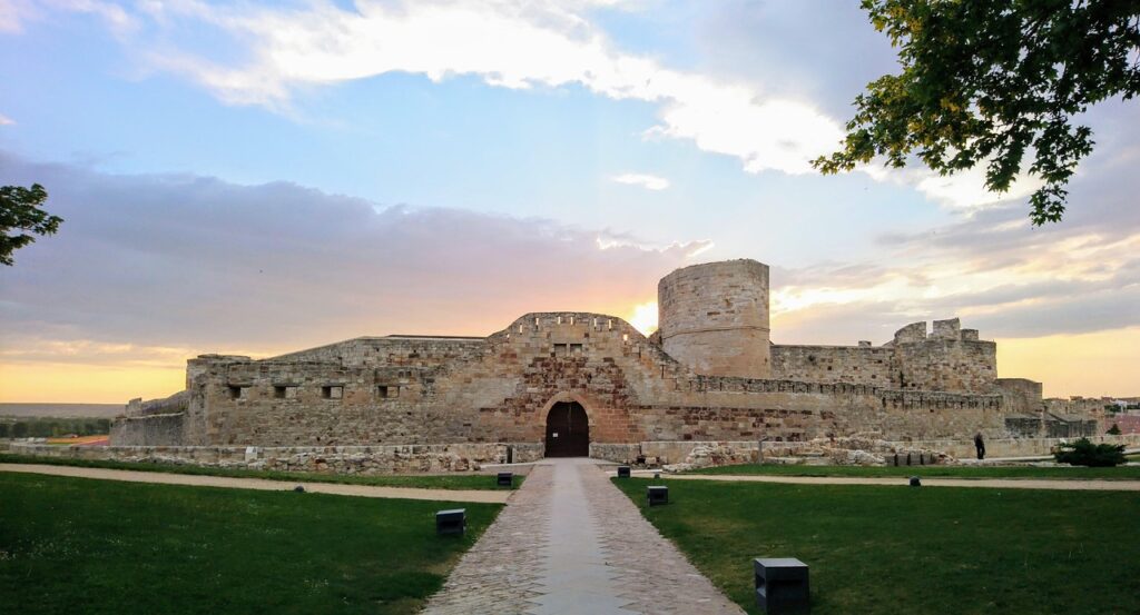 A panoramic view of Zamora, Spain with Romanesque church towers, medieval stone walls, and the Duero River flowing beneath a historic bridge — perfect for a Zamora Spain travel guide.